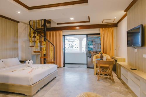 a bedroom with a bed and a tv and a table at Royal Prince Residence, Patong Beach in Patong Beach