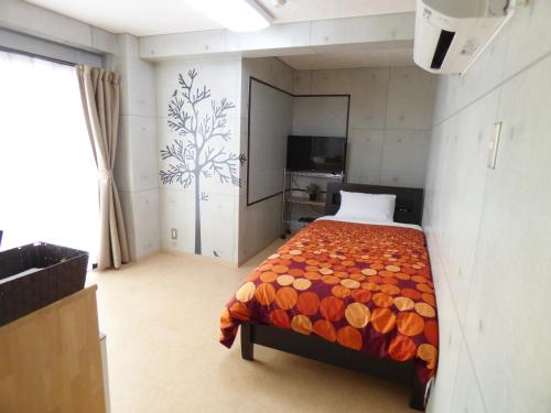 1 dormitorio con 1 cama y TV en Kyoto Uraraka Guest House en Kioto