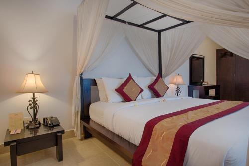 a bedroom with a large bed with a canopy at The Tukad Villa in Seminyak