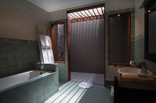 a bathroom with a bath tub and a sink at The Tukad Villa in Seminyak