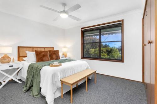 a white bedroom with a bed and a window at Sea Change in Shoal Bay