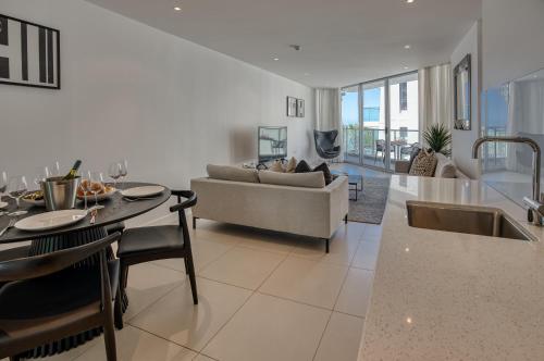 a kitchen and living room with a couch and a table at On The Beach Noosa Resort in Noosa Heads