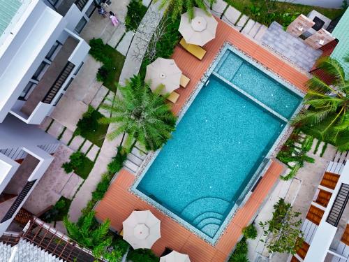 an overhead view of a swimming pool with palm trees and umbrellas at The R&B Boutique in Kampot
