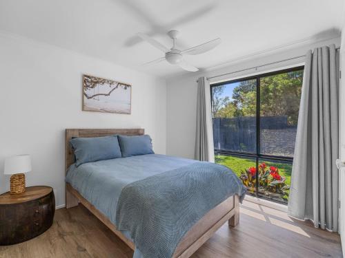 a bedroom with a bed and a large window at Tempting Tamara in Inverloch