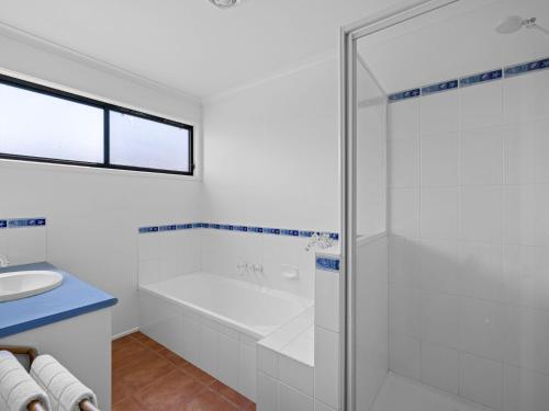 a white bathroom with a tub and a sink at Tempting Tamara in Inverloch