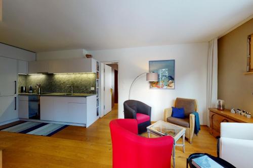 a kitchen and a living room with red chairs at Apartment Belvair 3 in Zuoz