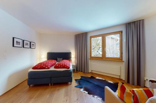 a bedroom with a bed with red pillows on it at Apartment Belvair 3 in Zuoz