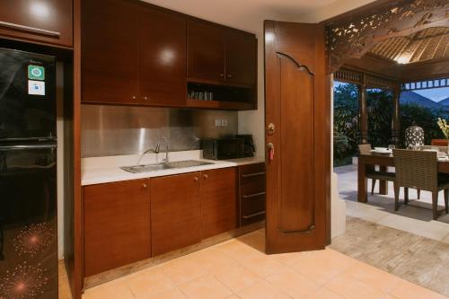 a kitchen with wooden cabinets and a dining room at Villa Anggrek Jimbaran in Jimbaran