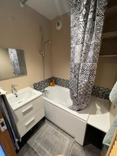 a bathroom with a bath tub and a sink at Appartement de montagne in Prémanon