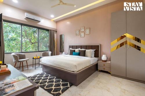 a bedroom with a king sized bed and a desk at Cashew Creek by VEO - Part of StayVista with Pool & WiFi in Alibaug