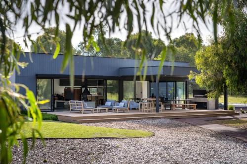 a house with glass walls and a wooden patio at The Tempest I Private Properties in Quindalup