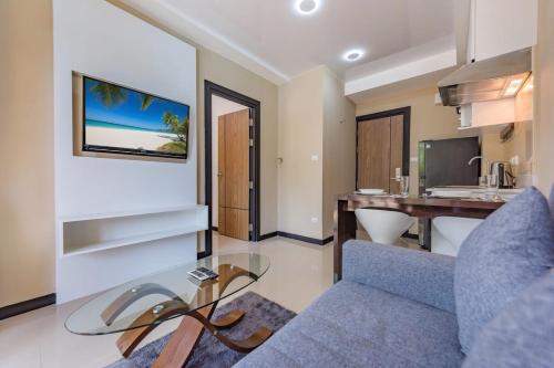 a living room with a blue couch and a desk at 1 BR Apt MBC 1503 near Mai Khao Beach and Airport in Mai Khao Beach