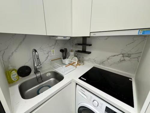a white kitchen with a sink and a dishwasher at Majestic Seoul Stay Central in Seoul