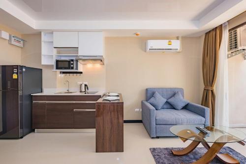 a living room with a blue chair and a kitchen at 1 BR Apt MBC 1503 near Mai Khao Beach and Airport in Mai Khao Beach