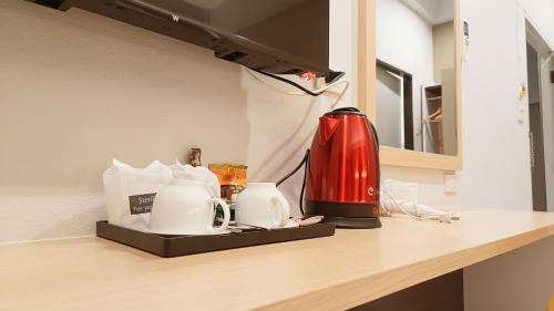 a kitchen counter with a red blender and cups on it at The Beginning Hotel in Betong