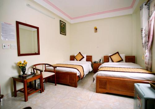 a bedroom with two beds and a mirror and a table at Bao An Hotel in Diện Biên Phủ