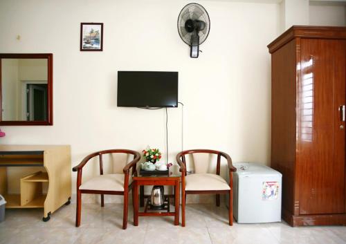 Habitación con 2 sillas, mesa y TV. en Bao An Hotel en Diện Biên Phủ