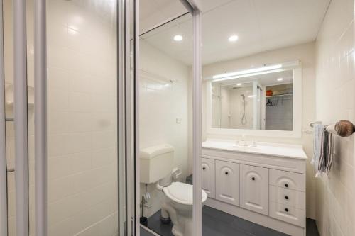 a bathroom with a toilet and a sink and a mirror at Boondelbah 4, 29 Soldiers Point Rd - waterfront bliss in Soldiers Point
