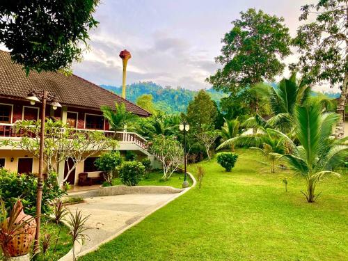 a resort with a green lawn next to a building at Happy Lagoon Bungalow in Khao Lak