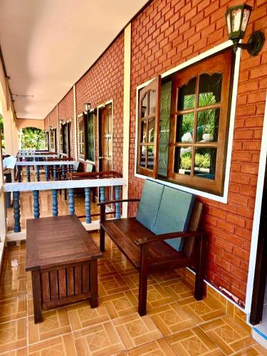 a porch with a bench and tables and a brick wall at Happy Lagoon Bungalow in Khao Lak