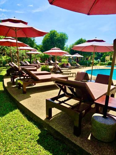 a row of lounge chairs and umbrellas next to a pool at Happy Lagoon Bungalow in Khao Lak