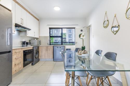 a kitchen with a glass table and chairs at Ballito Village Luxury Apartments in Ballito