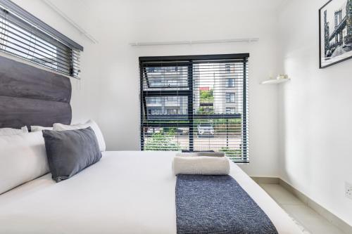 a white bedroom with a large bed and a window at Ballito Village Luxury Apartments in Ballito