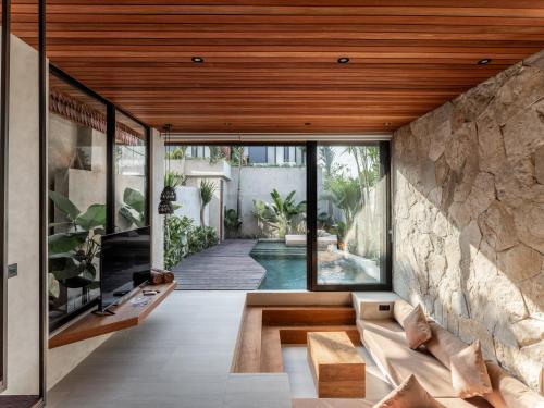 an open living room with a stone wall at Blacksand Villas Canggu in Canggu