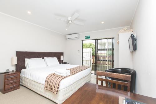 a white bedroom with a bed and a tv at Parkview Motor Inn in Pukekohe East