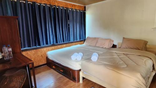a bedroom with a bed with white slippers on it at Bansuanphuhong Resort in Chiang Khan