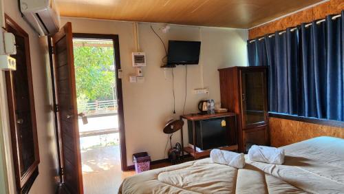 a bedroom with a bed and a tv and a window at Bansuanphuhong Resort in Chiang Khan