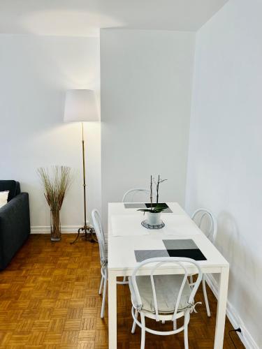 une salle à manger blanche avec une table et des chaises blanches dans l'établissement Magnifique appartement Paris 11ème, à Paris