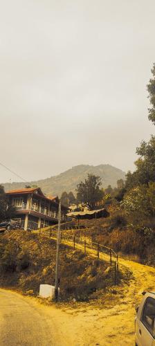 a car parked on a dirt road next to a building at Saanidhya Sunset View Villa in Mukteswar