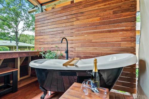 a bath tub sitting on a deck with a bottle of wine at Ingenia Holidays Noosa in Tewantin