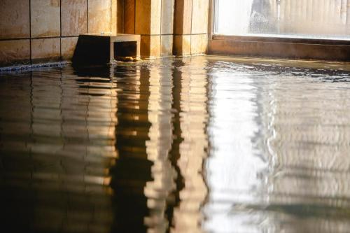 a flooded room with water on the floor and a window at Shikishimaso in Higashikawa
