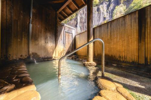a pool of water with a hand rail in a building at Shikishimaso in Higashikawa