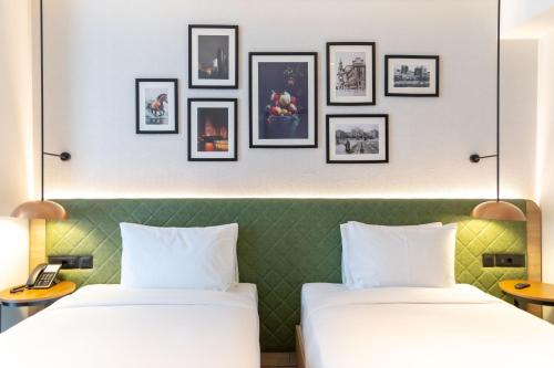 two beds in a hotel room with pictures on the wall at Hilton Garden Inn Baku in Baku