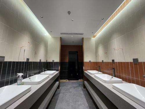 a bathroom with a row of sinks and mirrors at Denpa Inn-Lao Ximen Metro Station Branch in Shanghai