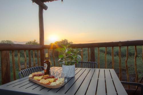 a picnic table with a basket of food and a bottle of beer at Pillows Luxury Safari Villa, Wood-Fired Hottub, Giraffe-Feeding-Tower, Large Private Pool in Marloth Park