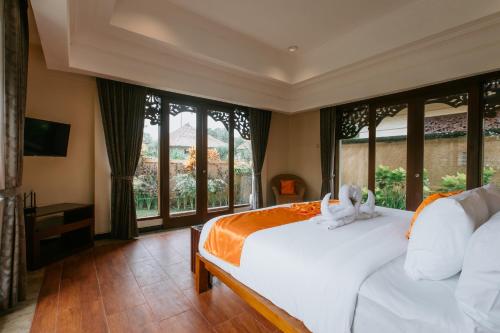 a bedroom with a white bed and large windows at Villa Anggrek Jimbaran in Jimbaran
