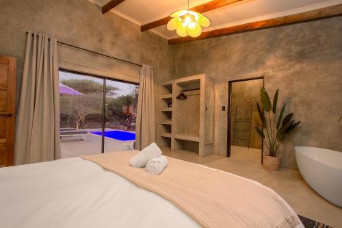 a bedroom with a large bed and a large window at Pillows Luxury Safari Villa, Wood-Fired Hottub, Giraffe-Feeding-Tower, Large Private Pool in Marloth Park