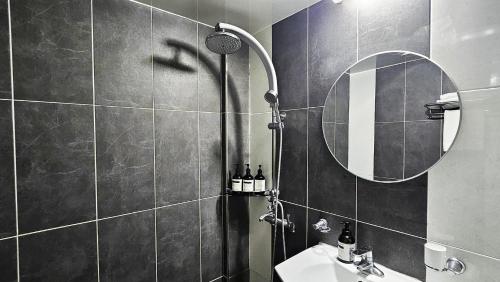 a bathroom with a shower with a sink and a mirror at Jeonju Pungnam Family Hotel in Jeonju