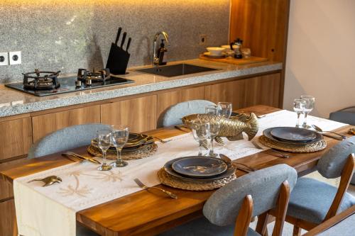 a wooden table with plates and glasses on it at Villa Amiti - Luxurious Haven Loft in Ricefields in Ubud