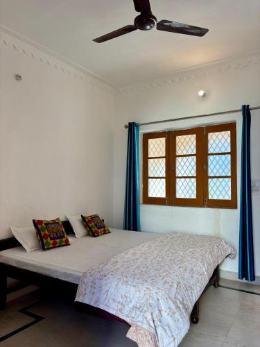 a bedroom with a bed with blue curtains and a ceiling fan at Prakruti Homestay in Rishīkesh