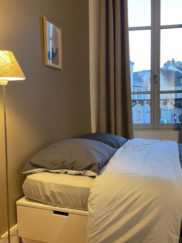 un lit dans une chambre avec une fenêtre et une lampe dans l'établissement Confortable 2 pièces au cœur de dreux #2, à Dreux