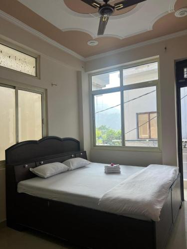 a bedroom with a large bed with two windows at Prakruti Homestay in Rishīkesh