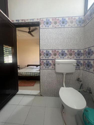 a bathroom with a toilet and a bedroom with a bed at Prakruti Homestay in Rishīkesh