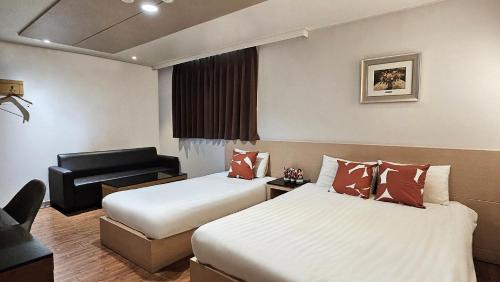 a hotel room with two beds and a chair at Jeonju Pungnam Family Hotel in Jeonju