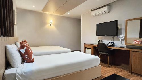a hotel room with two beds and a desk and a television at Jeonju Pungnam Family Hotel in Jeonju