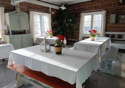 a large room with three tables with flowers on it at Pyrrön pirtti, koko talo in Oulainen
